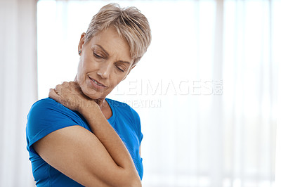 Buy stock photo Shot of a mature woman holding her neck feeling pained at home