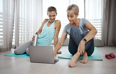 Buy stock photo Shot of two mature women browsing the internet for new workout ideas while exercising at home