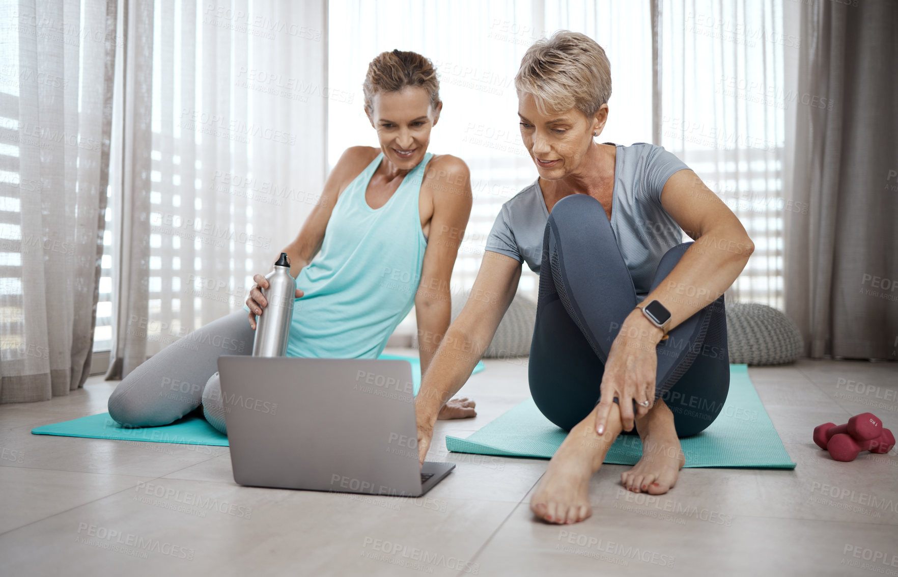 Buy stock photo Shot of two mature women browsing the internet for new workout ideas while exercising at home