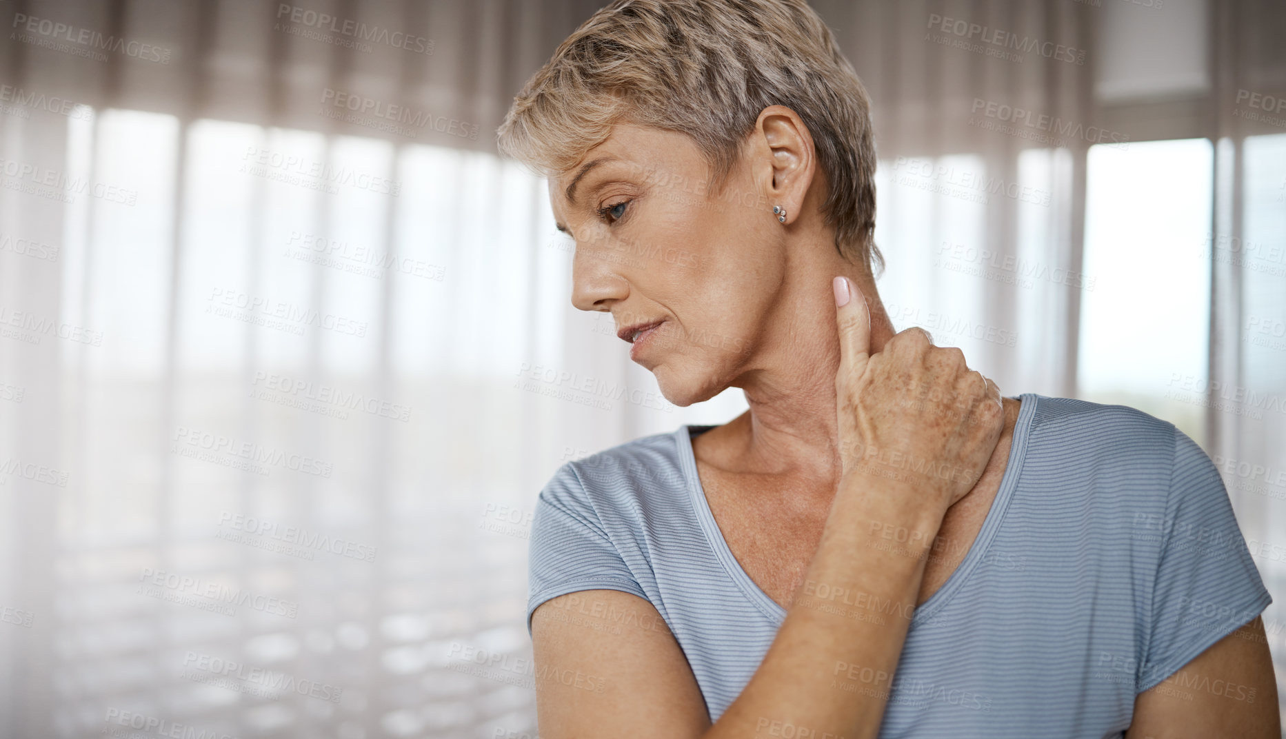 Buy stock photo Shot of a mature woman experiencing discomfort in her neck while working out at home