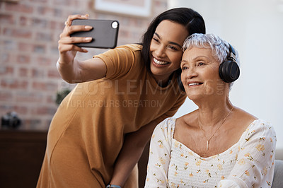 Buy stock photo Shot of a senior woman using a smartphone to take selfies with her daughter at home