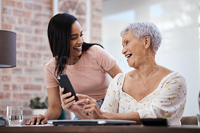 Buy stock photo Shot of a young woman using a smartphone with her elderly mother while going through finances at home