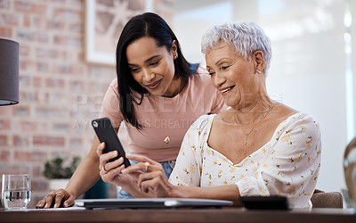 Buy stock photo Shot of a young woman using a smartphone with her elderly mother while going through finances at home