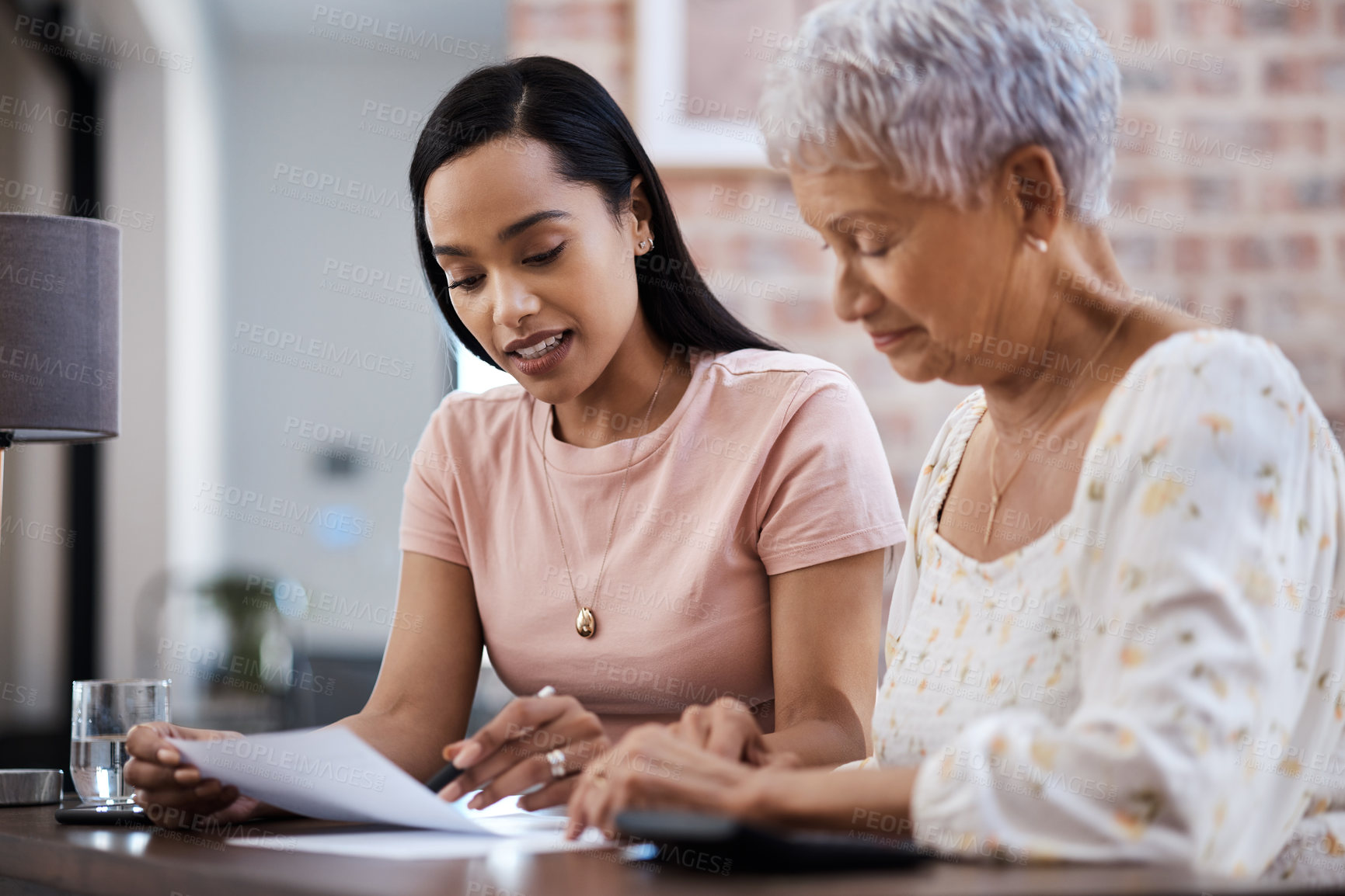 Buy stock photo Shot of a young woman going over paperwork with her elderly mother at home