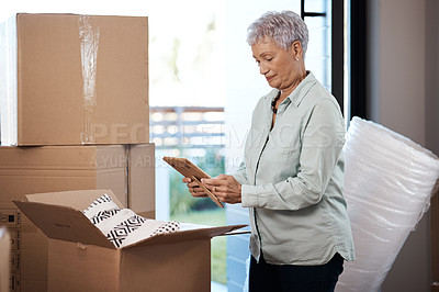 Buy stock photo Shot of a senior woman looking at a photograph while packing boxes on moving day