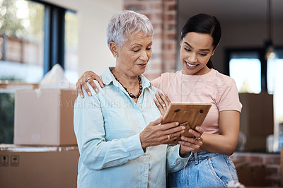 Buy stock photo Shot of a senior woman looking at a photograph with her daughter while packing boxes on moving day