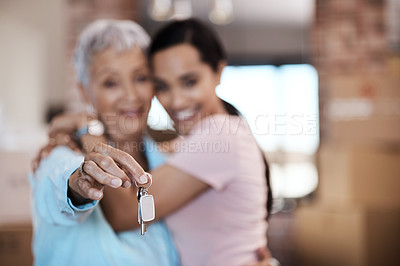 Buy stock photo Shot of a senior woman standing next to her daughter and holding up the keys to her new home