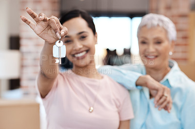 Buy stock photo Shot of a senior woman standing next to her daughter and holding up the keys to her new home