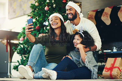 Buy stock photo Selfie, family and christmas with a mother, father and daughter sitting for a photograph at home with a gift by a tree. Kids, fun and love with a girl, woman and man posing for a festive picture
