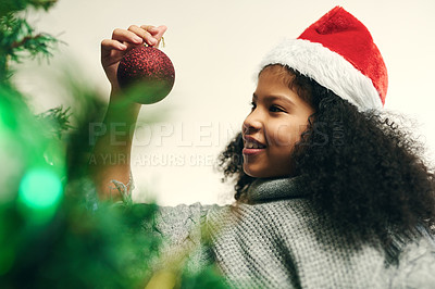 Buy stock photo Christmas, decoration and girl with smile for tree, holiday and celebration in a house. Happy, festive and child decorating the Christmas tree to celebrate the festive season in a house for fun