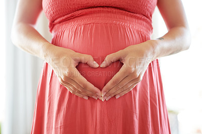 Buy stock photo Shot of a mother to be forming a heart shape over her pregnant belly