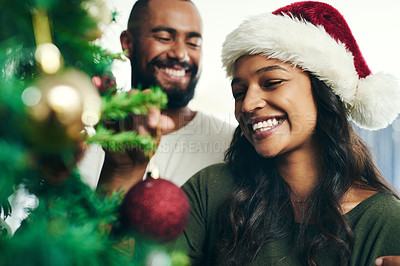 Buy stock photo Christmas, tree and smile with a black couple decorating in the home together for the festive season. Love, celebration and holidays with a happy man and woman in a santa hat while bonding in a house