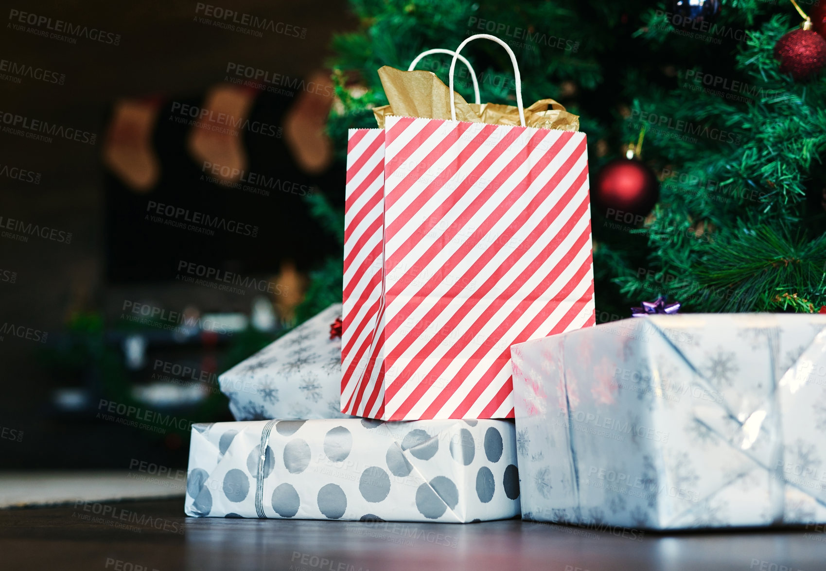 Buy stock photo Christmas, gift and tree on floor in home for surprise, giving and celebration in holiday season. Bag, box and present on flooring by christmas tree for happiness, tradition and happy spirit in house