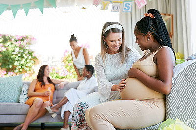 Buy stock photo Shot of a young woman feeling her friends baby move in her belly during her baby shower