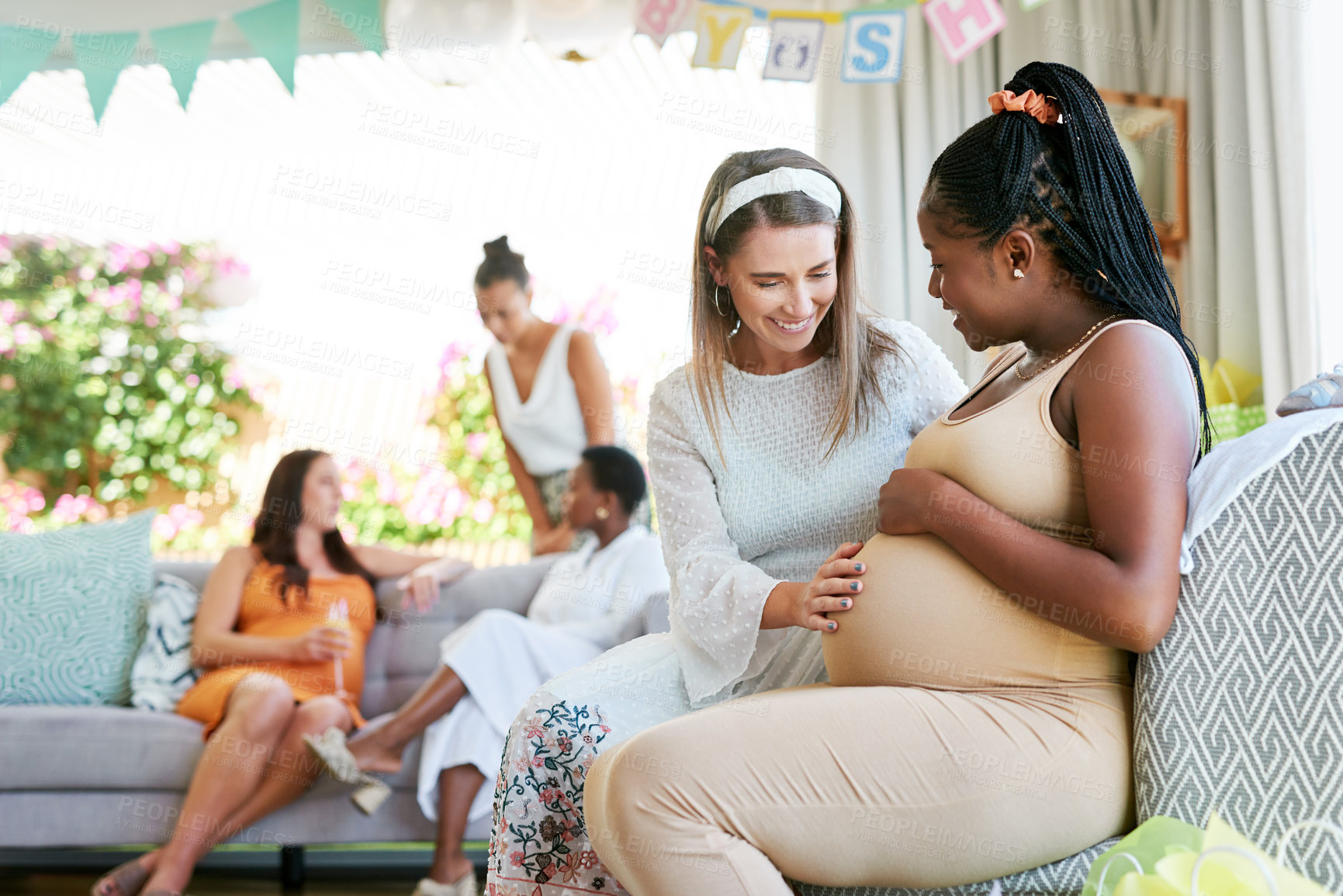 Buy stock photo Shot of a young woman feeling her friends baby move in her belly during her baby shower