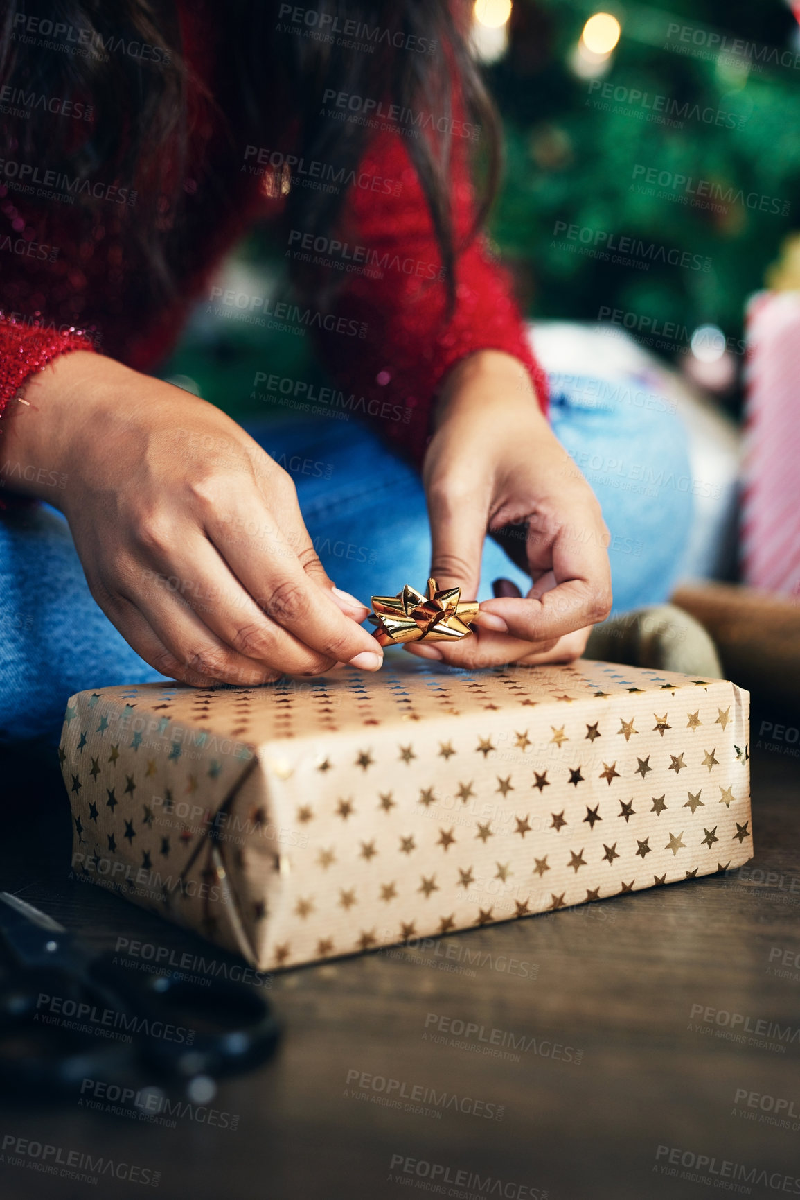 Buy stock photo Hand, christmas and gift with a woman preparing surprise for festive season while sitting on the floor. Hands, closeup and wrapping xmas present with a bow to get ready for a traditional december 