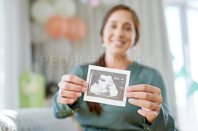 Buy stock photo Shot of a young mother to be holding an ultrasound of her unborn child