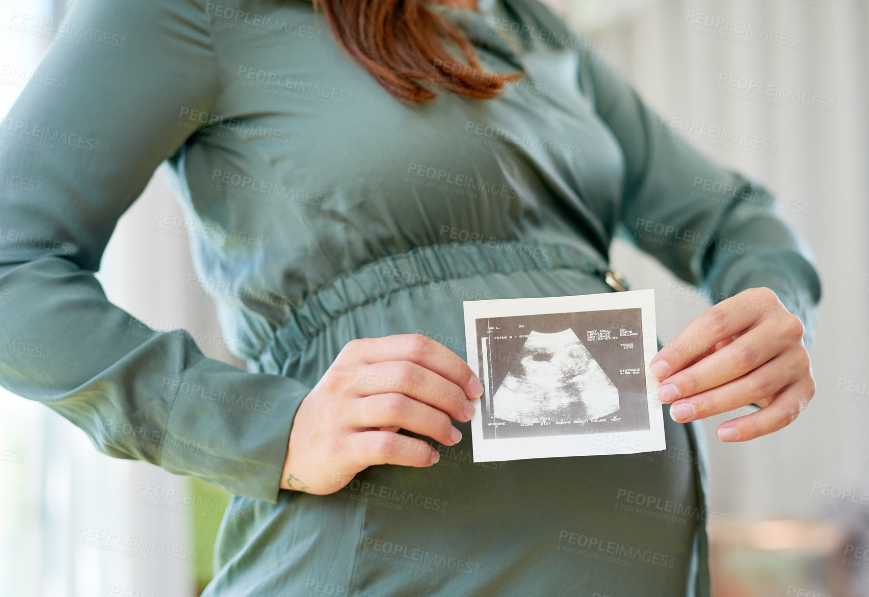 Buy stock photo Shot of a mother to be holding an ultrasound of her unborn child