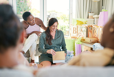 Buy stock photo Shot of a young mother opening a gift from her friends at her baby shower