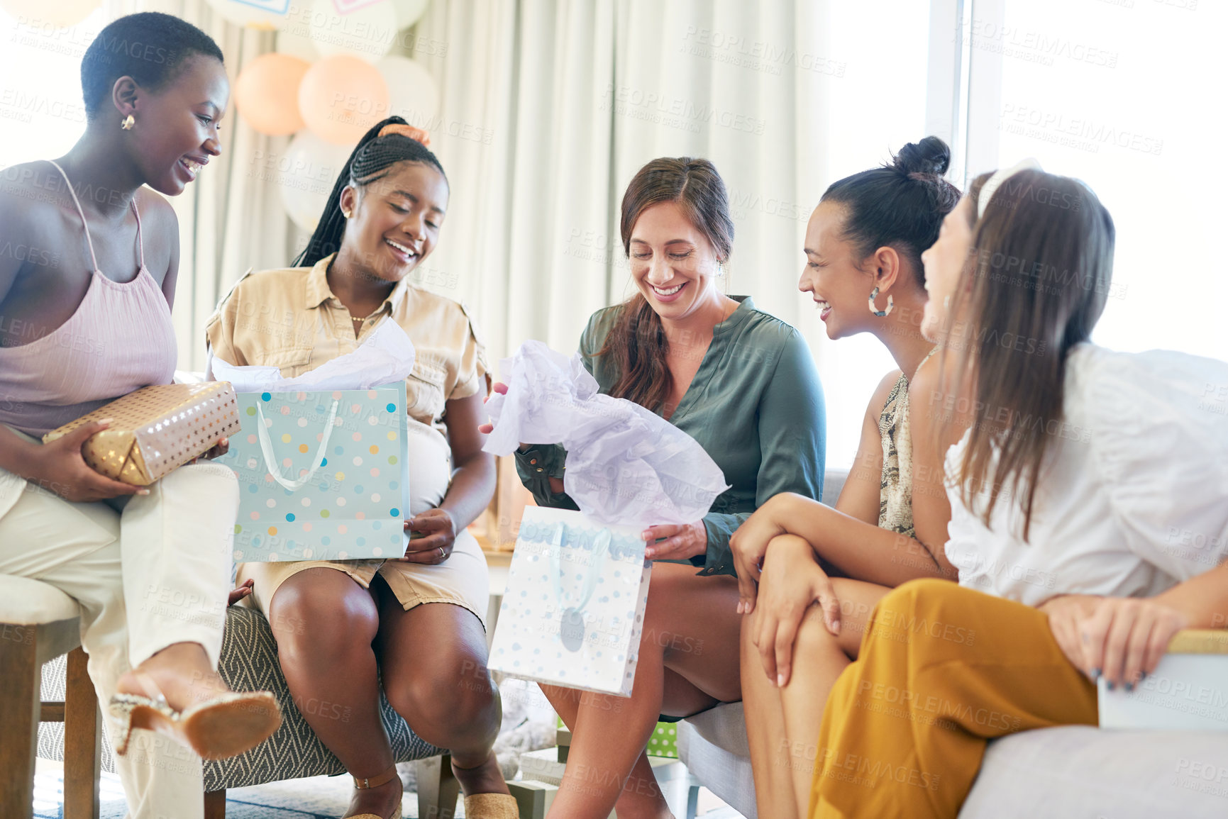 Buy stock photo Shot of a young mother opening a gift from her friends at her baby shower