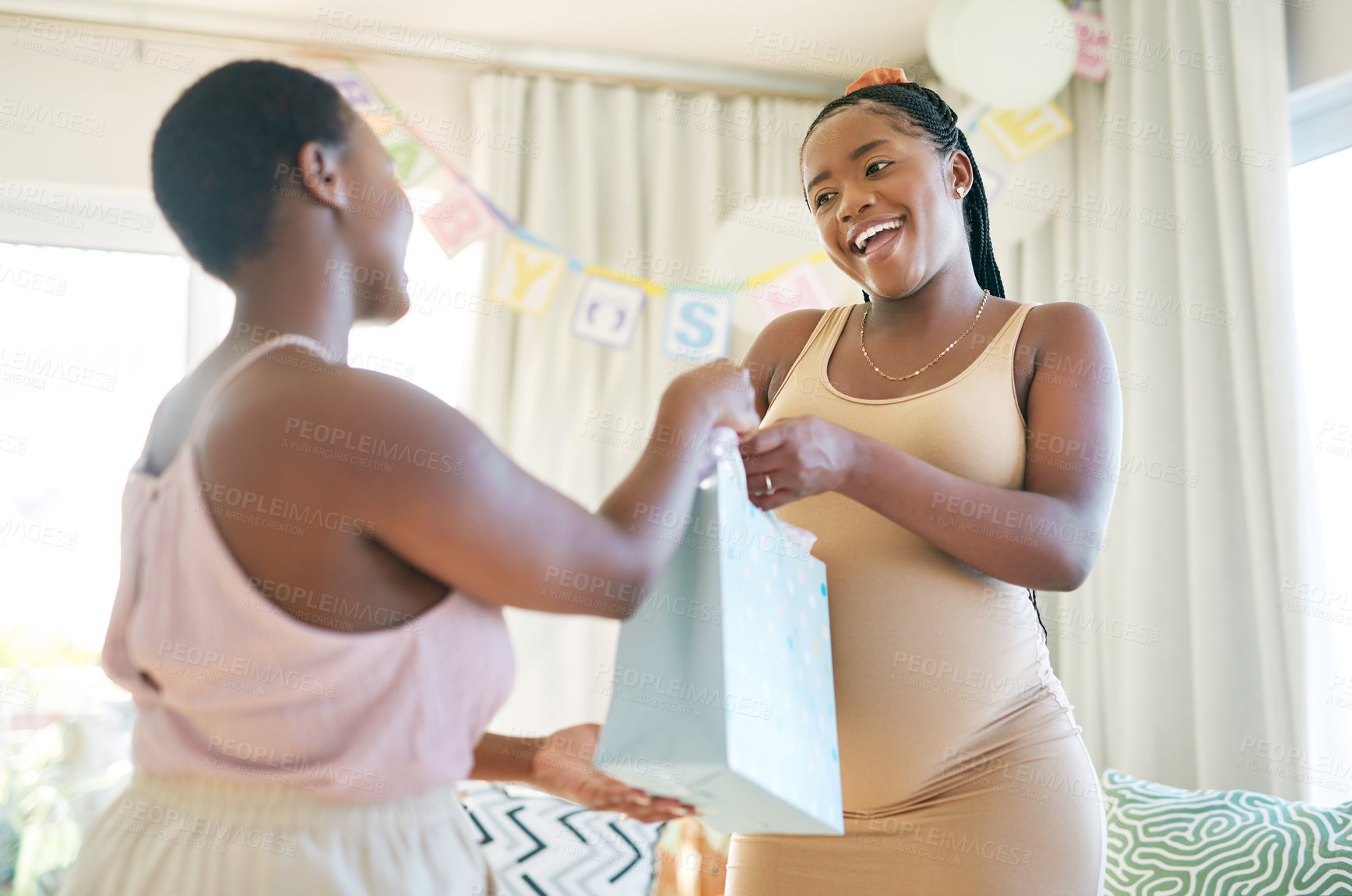 Buy stock photo Shot of a woman giving her friend a gift at her baby shower