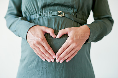 Buy stock photo Shot of a mother to be forming a heart shape over her pregnant belly