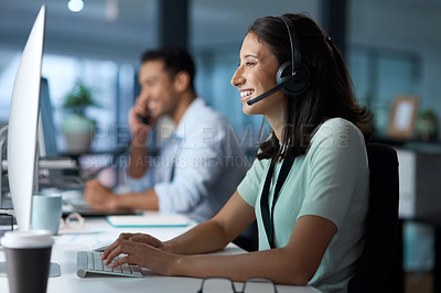 Buy stock photo Shot of a young woman using a headset and computer in a modern office