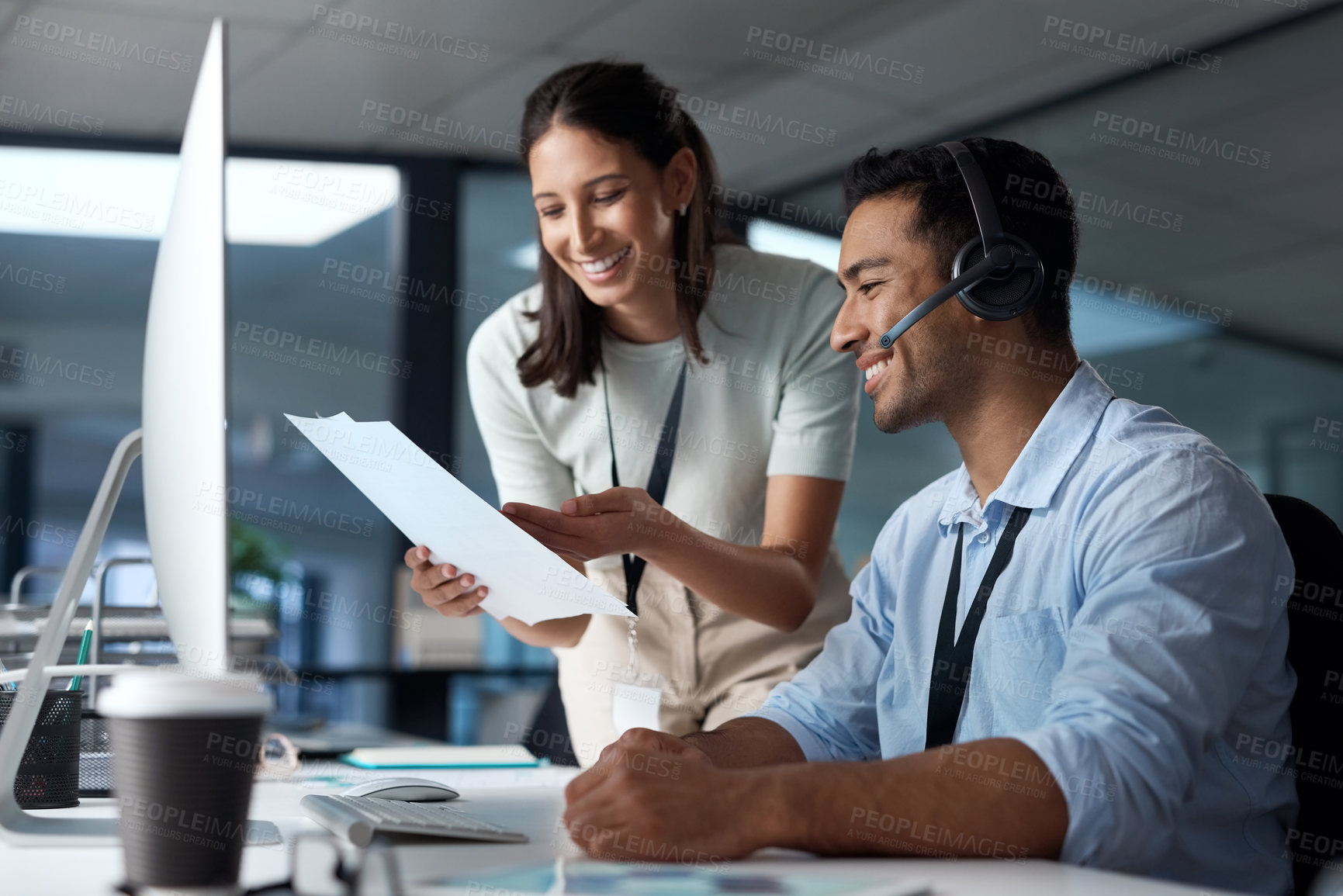 Buy stock photo Shot of a young man and woman reading a document while working in a call centre