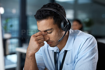 Buy stock photo Shot of a young man using a headset and looking stressed in a modern office