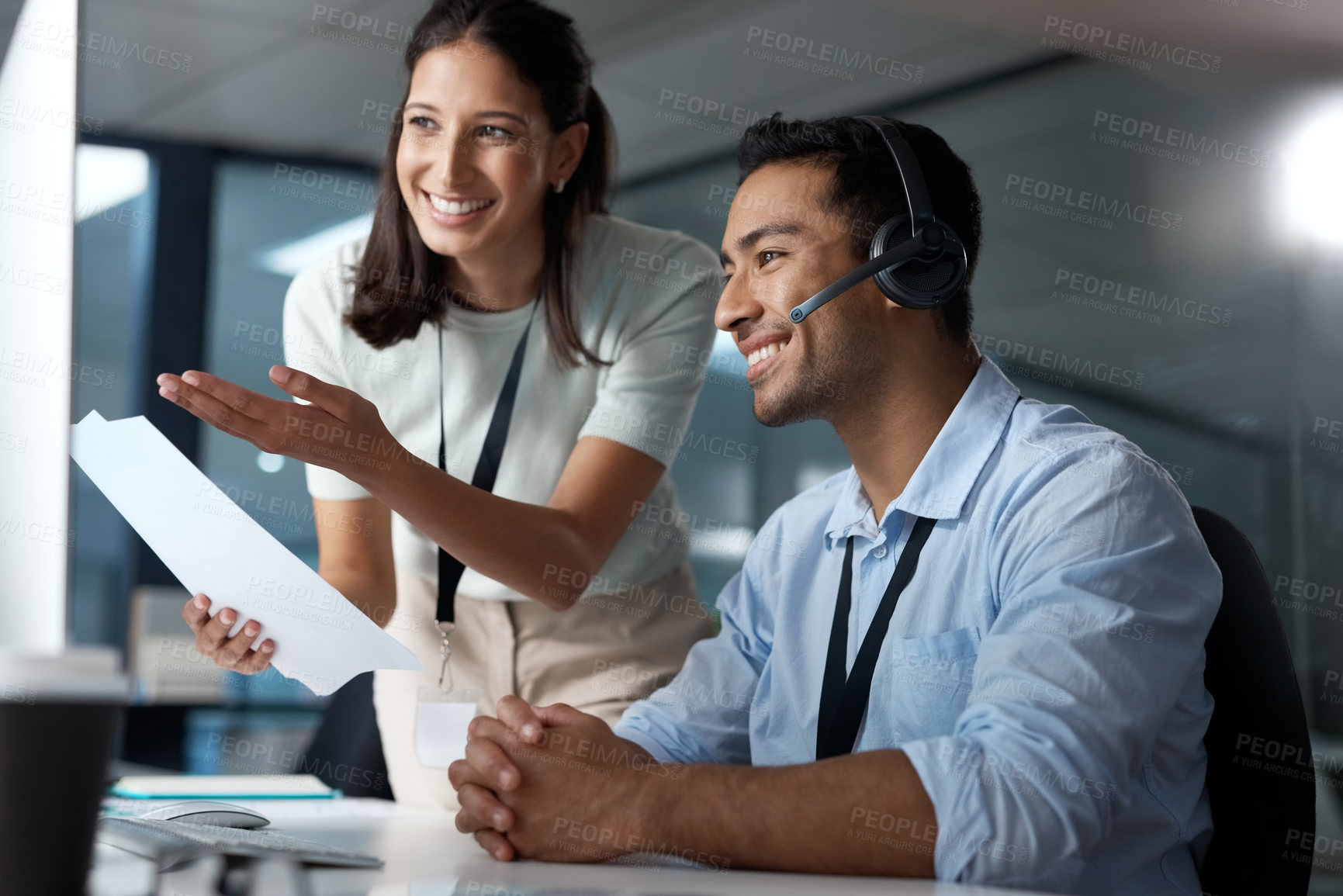 Buy stock photo Shot of a young man and woman reading a document while working in a call centre