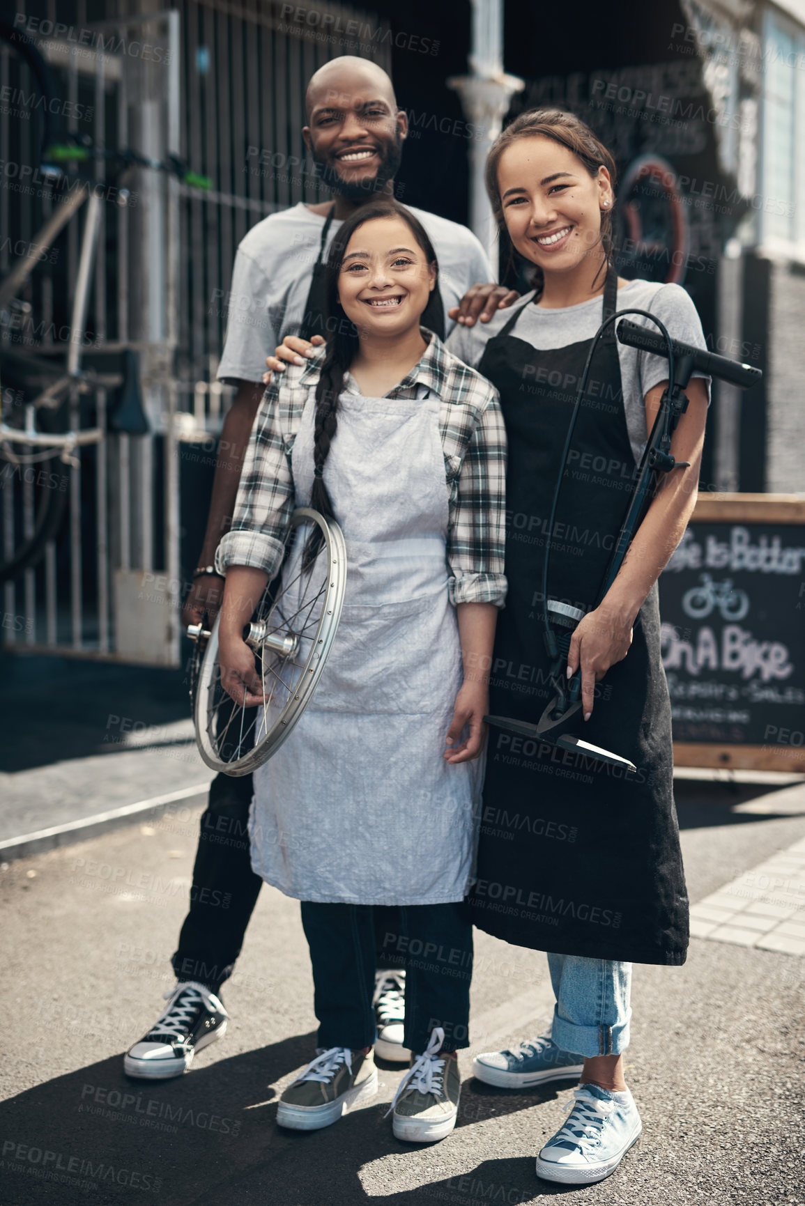 Buy stock photo Portrait of three young workers standing in front of their bicycle repair shop outside