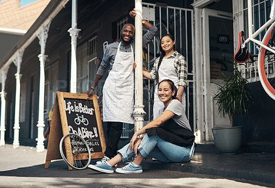 Buy stock photo Portrait of three young workers sitting outside of their bicycle repair shop