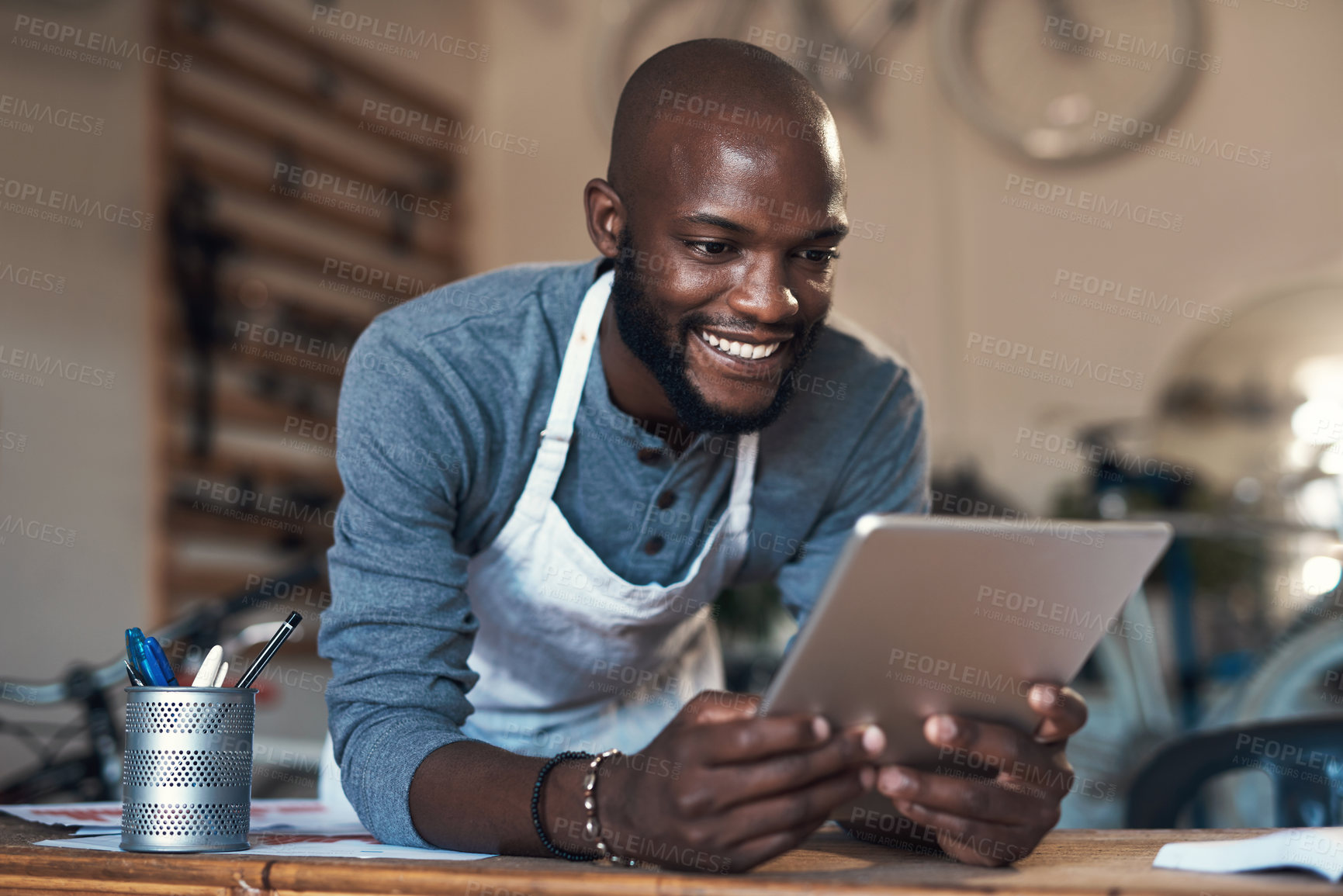 Buy stock photo Shot of a young man using a digital tablet at work
