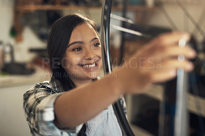 Buy stock photo Shot of a young woman woking at a bicycle repair shop