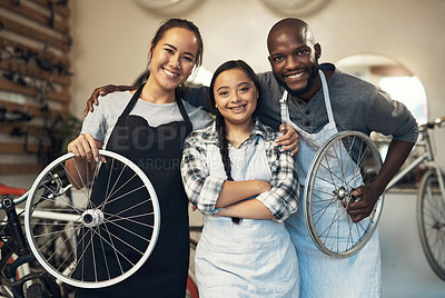 Buy stock photo Portrait of three young workers at a bicycle repair shop