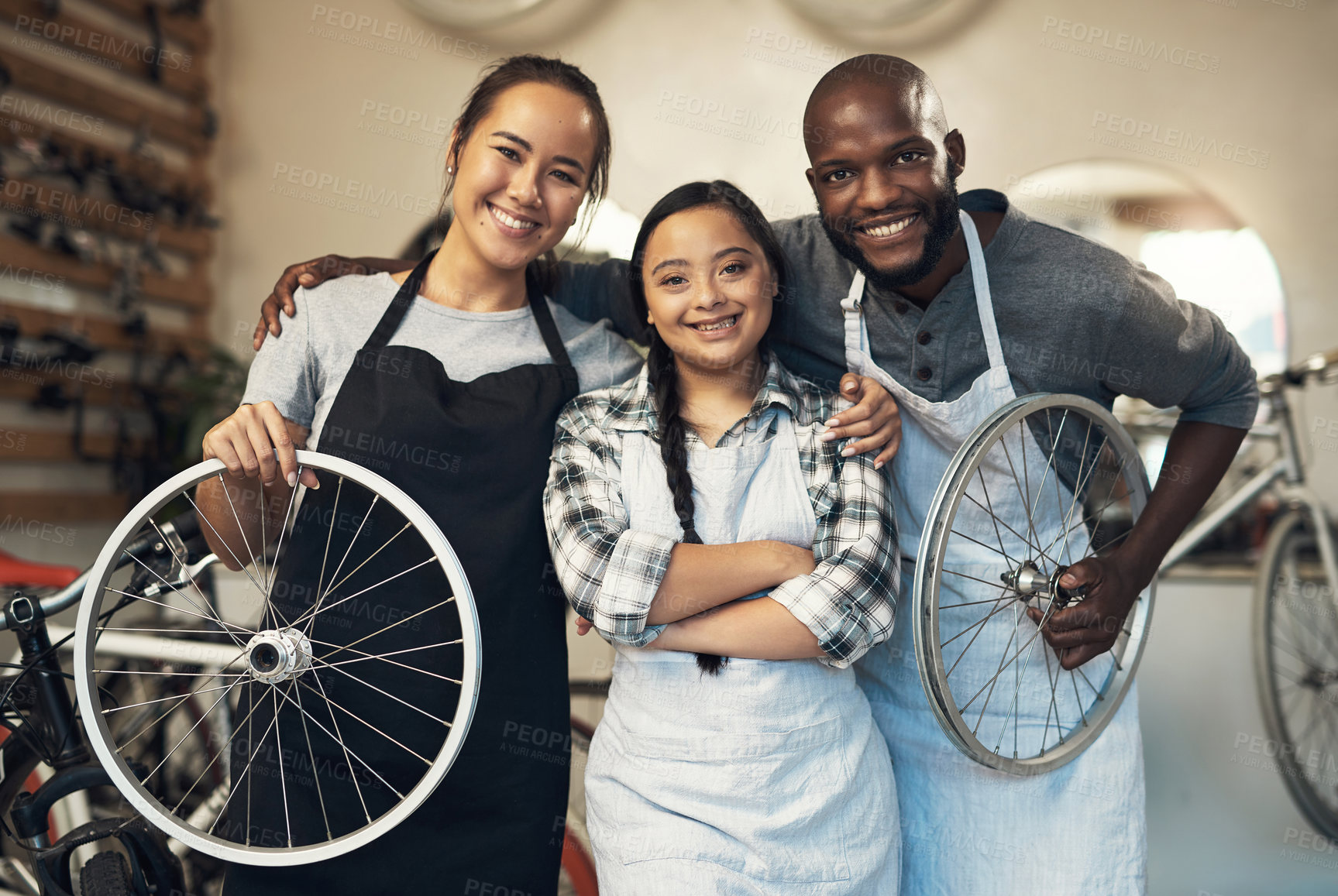 Buy stock photo Portrait of three young workers at a bicycle repair shop