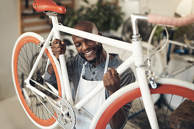 Buy stock photo Shot of a handsome young man standing alone in his shop and getting ready to repair a bicycle