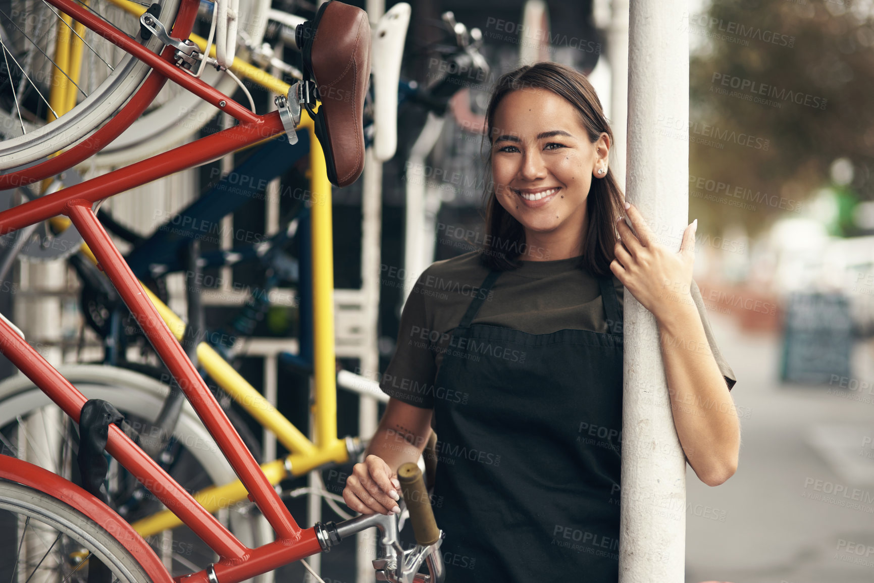 Buy stock photo Shot of an attractive young woman standing outside her bicycle shop during the day