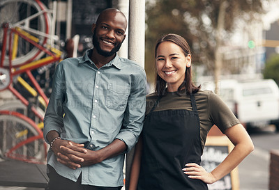 Buy stock photo Shot of two young business owners standing outside their bicycle shop during the day