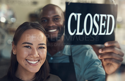 Buy stock photo Shot of two young colleagues standing together and turning the sign on the door to their bicycle shop