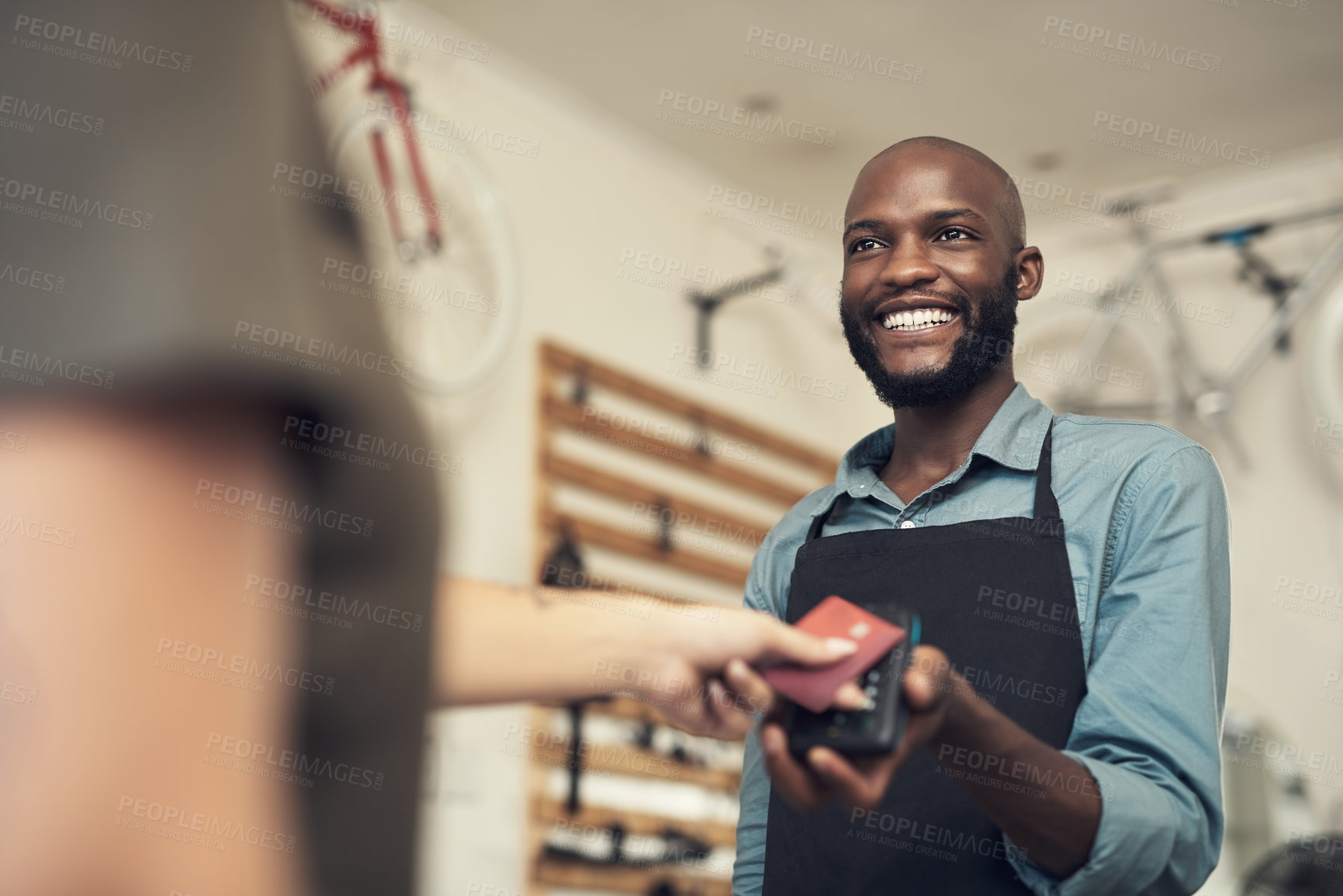 Buy stock photo Shot of a handsome young man standing in his bicycle shop and assisting a customer with her purchase