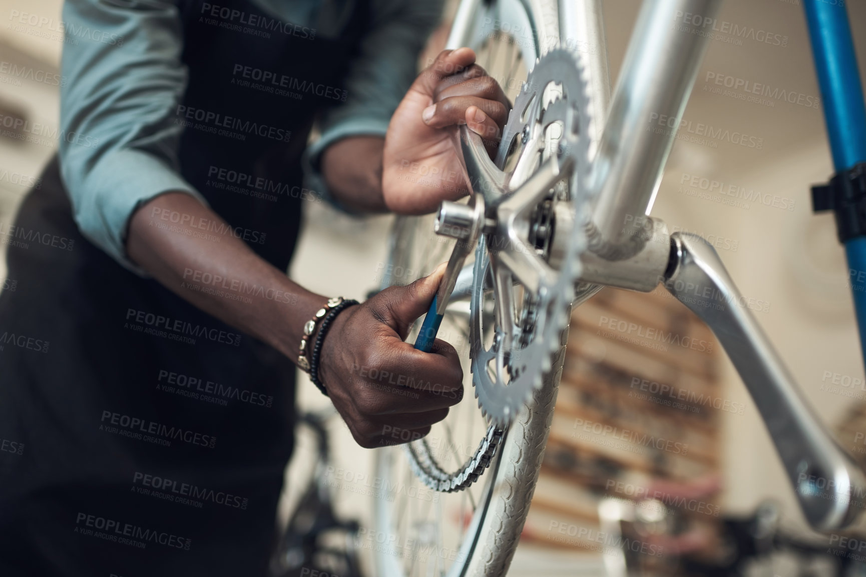Buy stock photo Shot of an unrecognizable man standing alone in his shop and repairing a bicycle wheel
