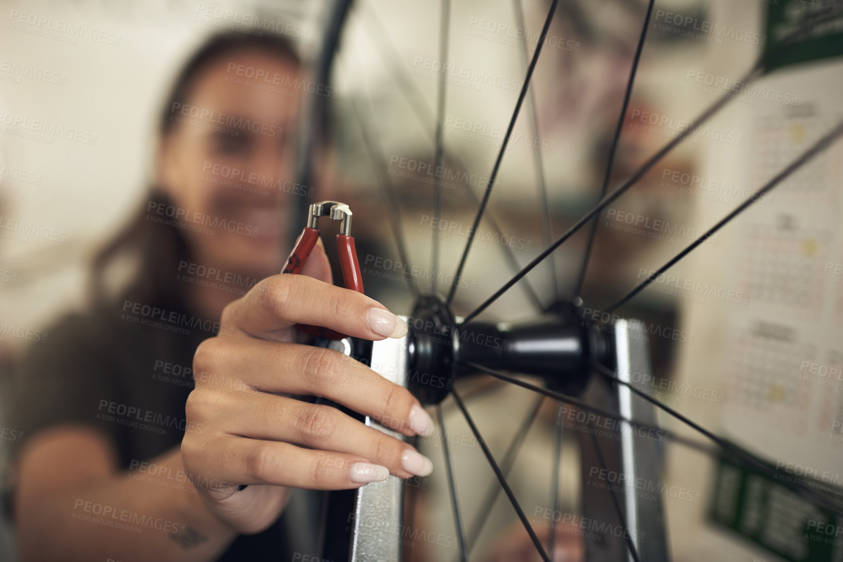 Buy stock photo Shot of an unrecognizable woman standing alone in her shop and repairing a bicycle wheel