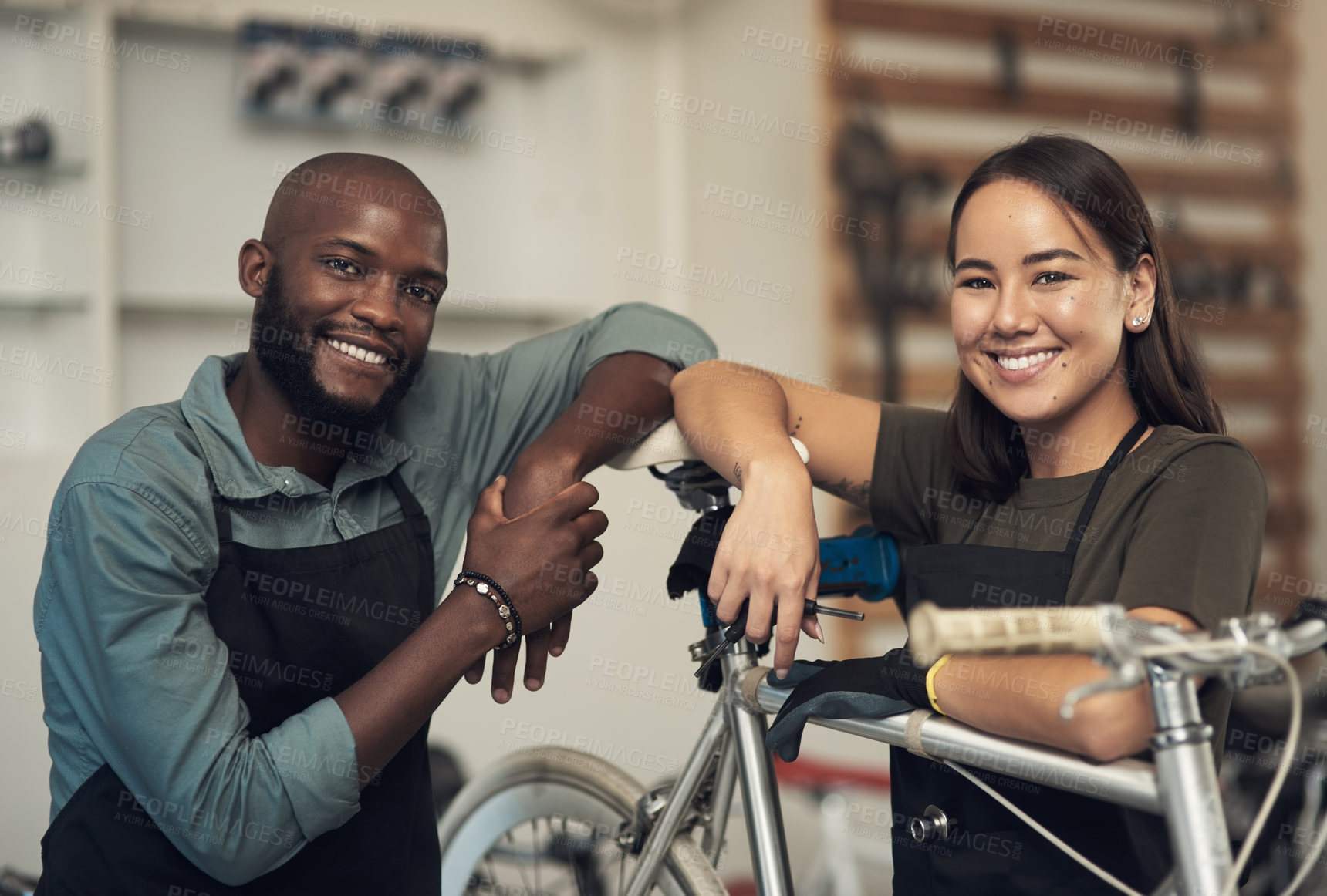 Buy stock photo Shot of two young business owners standing together in their bicycle shop during the day