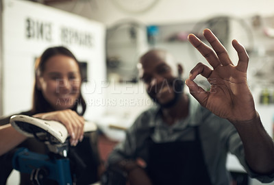 Buy stock photo Shot of two unrecognizable business owners standing together in their bicycle shop and making an okay hand gesture