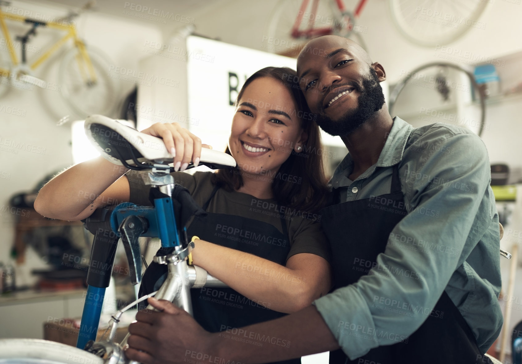 Buy stock photo Shot of a young couple standing together in their bicycle shop during the day