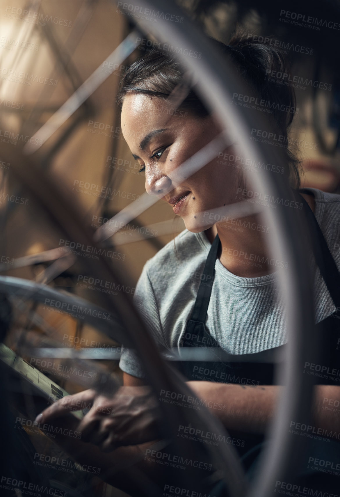 Buy stock photo Cropped shot of a happy young woman using a digital tablet and fixing a bike at a bicycle repair shop