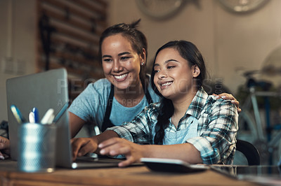 Buy stock photo Shot of two young workers using a laptop at work