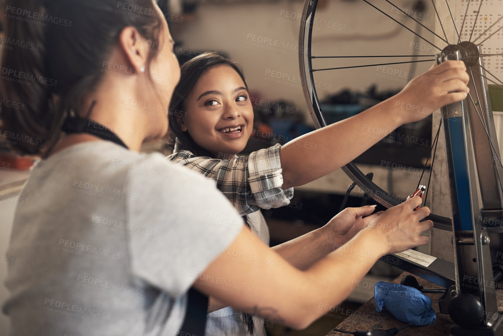Buy stock photo Shot of two young female  workers fixing a bike at a bicycle repair shop