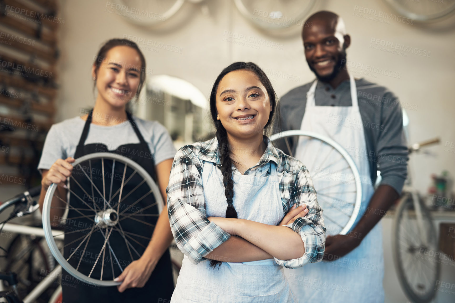 Buy stock photo Portrait of three young colleagues working together at a bicycle repair shop